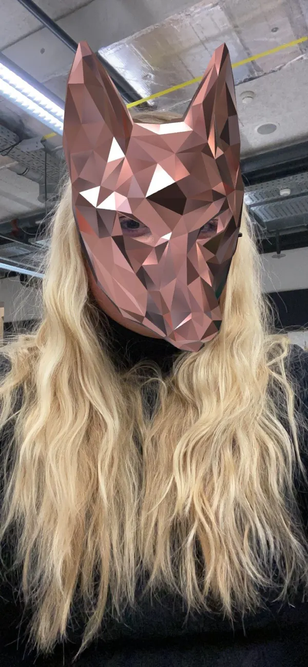 Selfie from the Spark AR prototype, taken in a workshop hall: a woman with long blonde hair, the fox mask, here in a pale copper tone, covers her face.