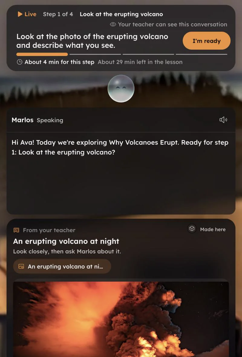 Student view in a live lesson, upright: the step goal Look at the photo of the erupting volcano and describe what you see, an I'm ready button, the note Your teacher can see this conversation, Marlos speaking, and a photo of a volcano erupting at night shared by the teacher.
