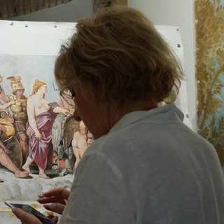 A woman working close to a large painted panel.
