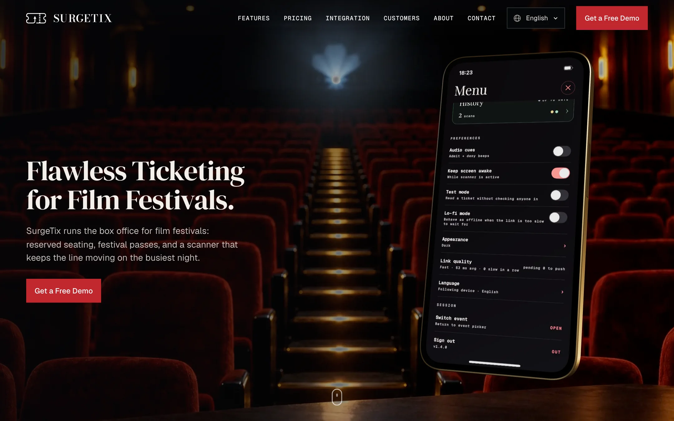 The top of the SurgeTix home page: the navigation with the logo, six links, a language picker and a red Get a Free Demo button; the headline Flawless Ticketing for Film Festivals in a large serif, a line of text and a red button on the left; a phone in a gold frame on the right showing a scanned ticket marked Admitted, over a dim cinema hall with red seats.