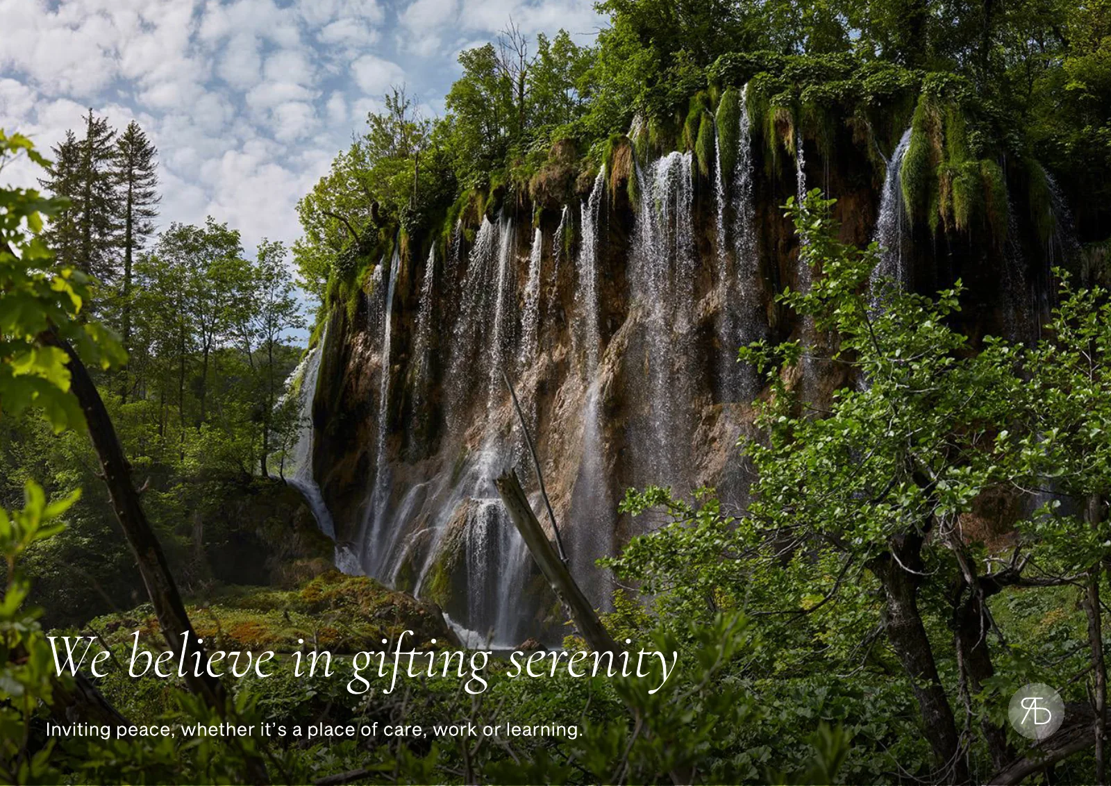 Page of the pitch deck: a photograph of a wide waterfall falling through green forest, with the serif italic line We believe in gifting serenity.