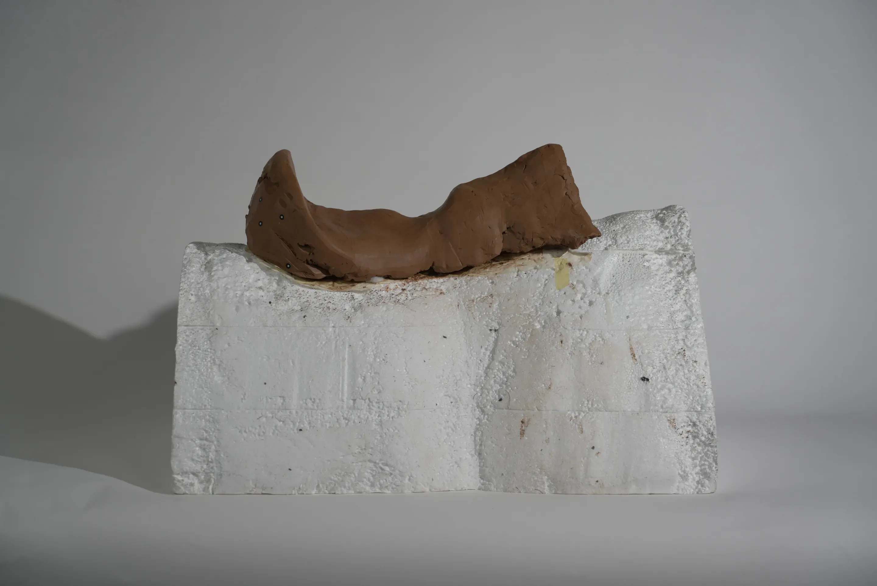 Prototype step: a saddle shape modelled in brown clay on the foam block.