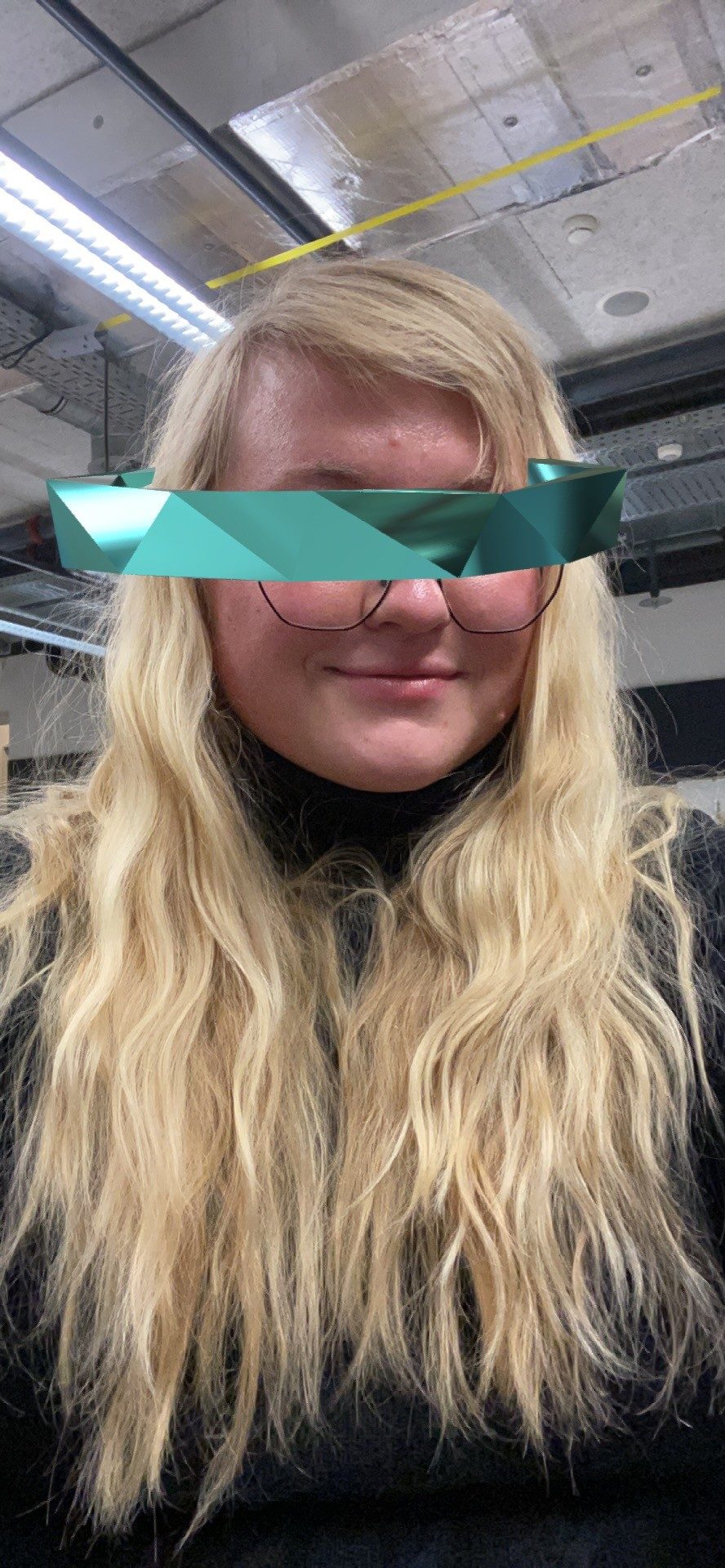 Selfie from the Spark AR prototype: the teal faceted band sits across the eyes of the woman with long blonde hair, who smiles.