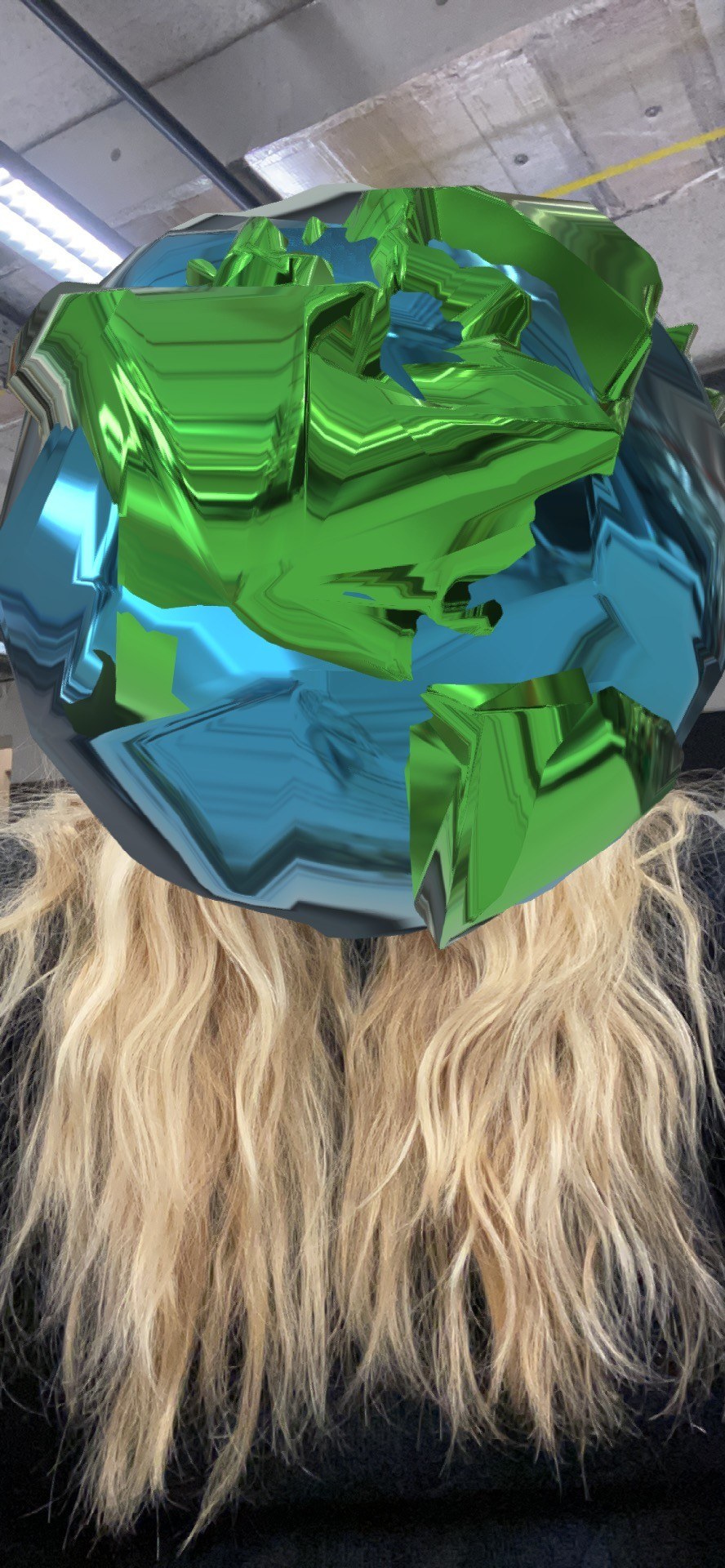 Selfie from the Spark AR prototype: the green and blue globe covers the whole head of the woman with long blonde hair.
