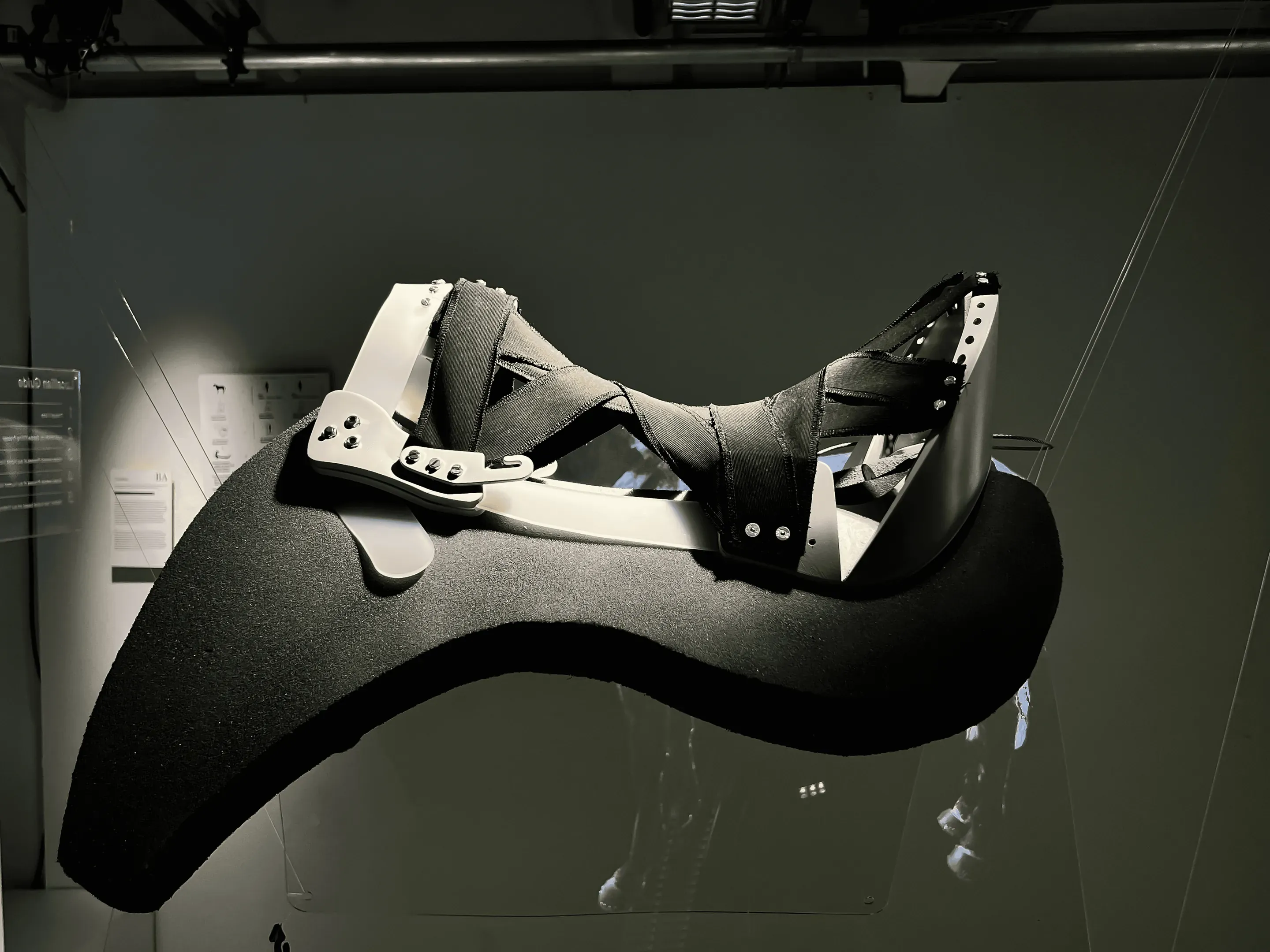 The saddle tree prototype on a dark grey pad, hanging in the exhibition space.