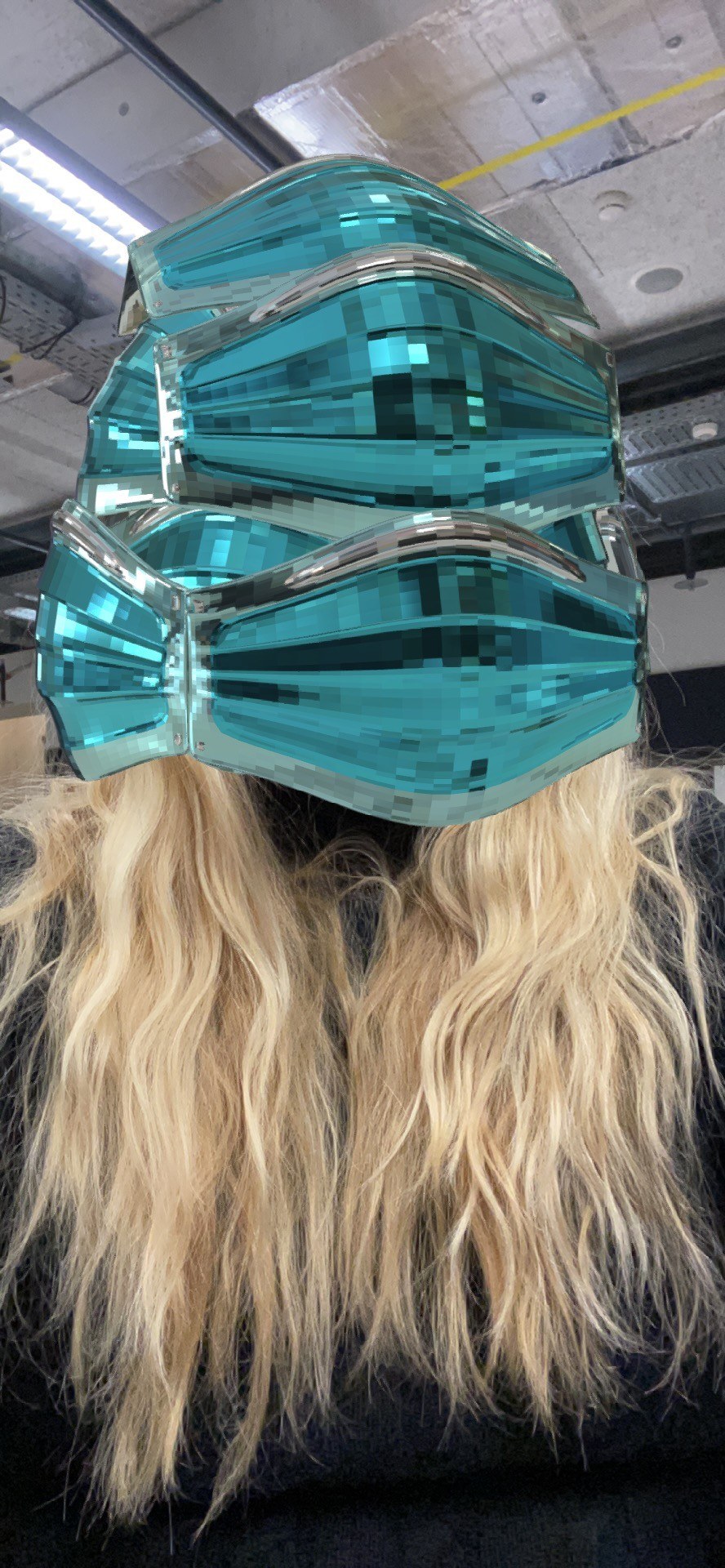 Selfie from the Spark AR prototype: the stack of teal glass masks covers the face of the woman with long blonde hair.