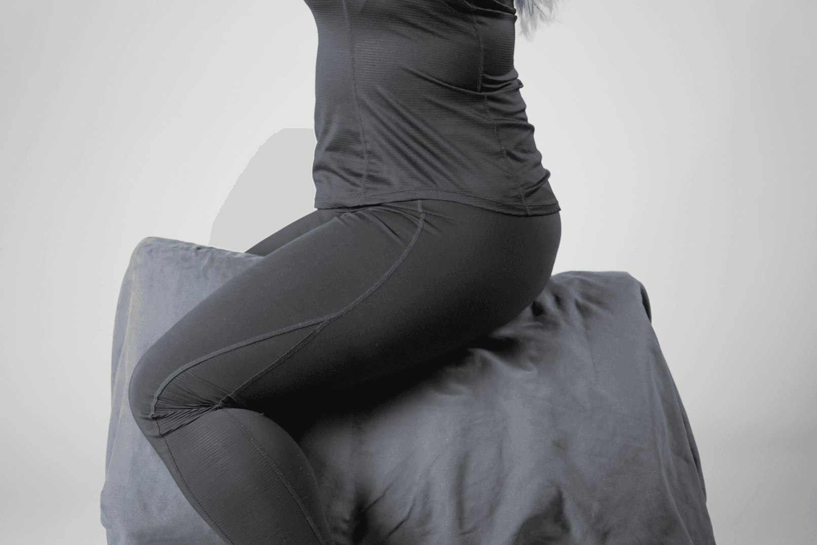 Seat study: a woman sits astride the block, upright, seen from the side.
