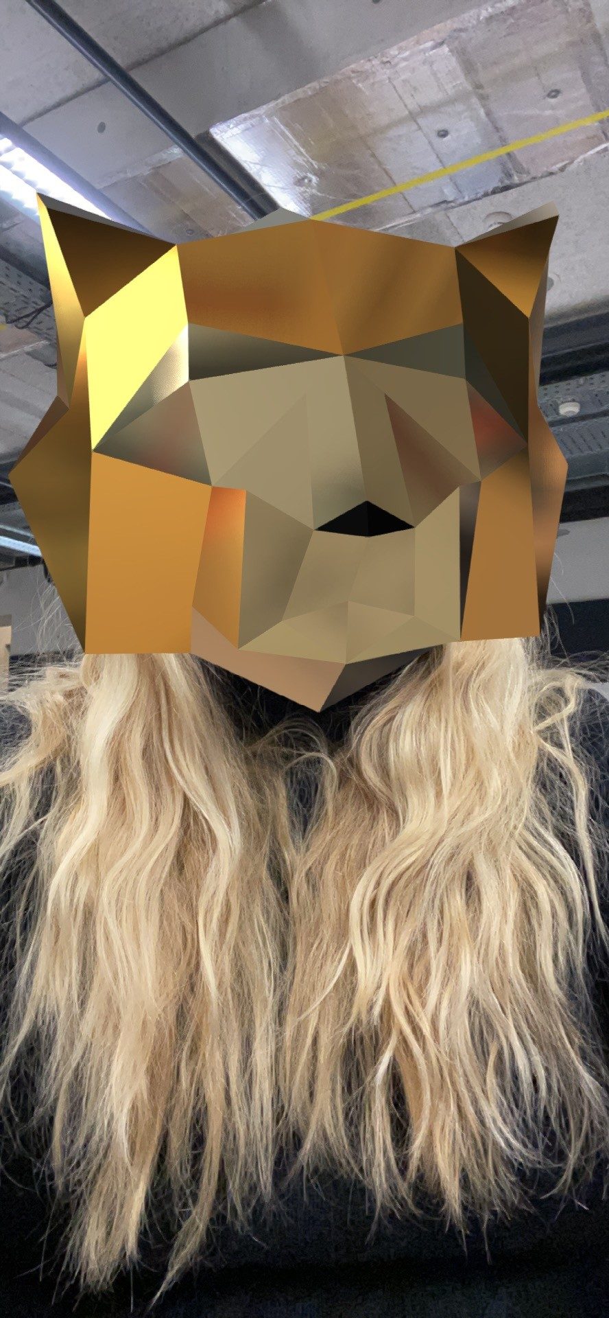 Selfie from the Spark AR prototype: the golden low poly animal head covers the face of the woman with long blonde hair.