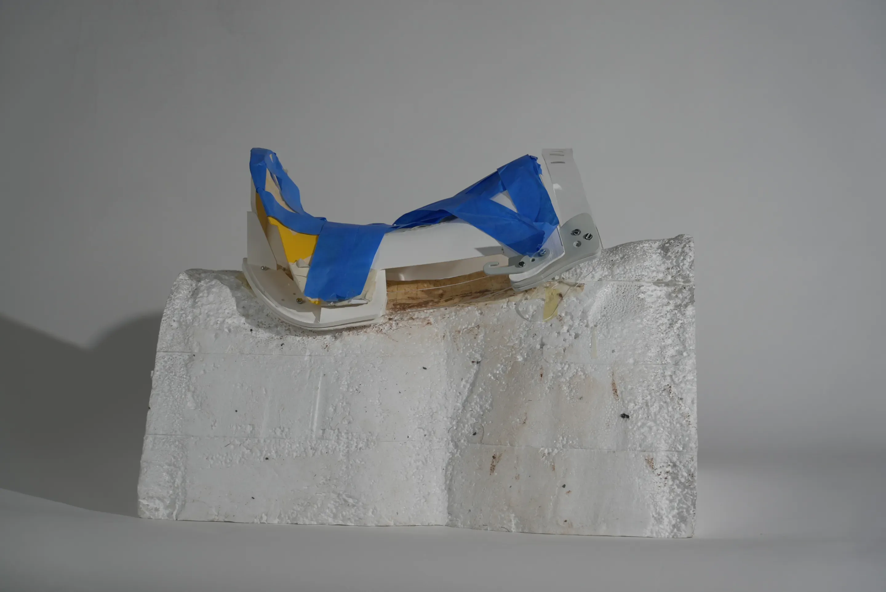 Prototype step: a white printed tree with a blue taped seat web and yellow parts, on the foam block.
