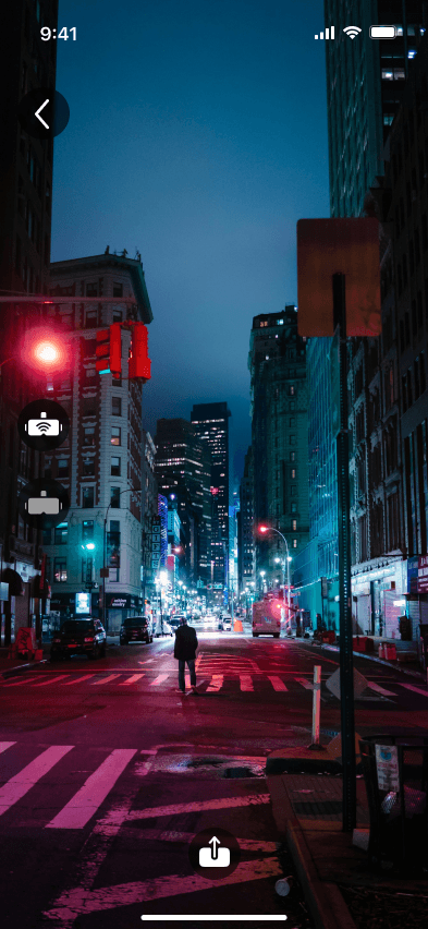 AR camera view of the night street without overlays: a back arrow, two round headset icons on the left edge and an import icon at the bottom.