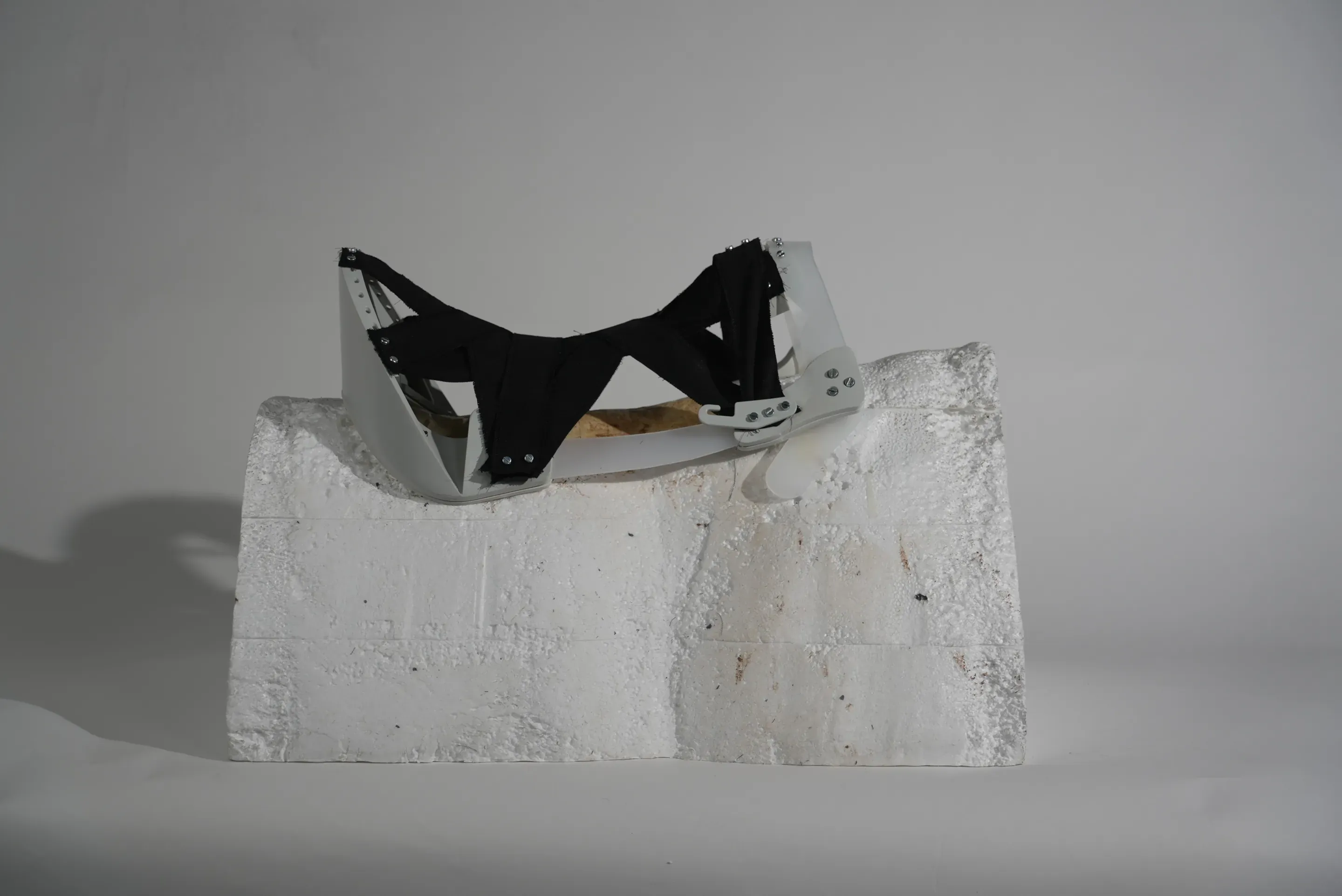 Prototype step: a tree with a black seat web between grey and white end pieces, on the foam block.