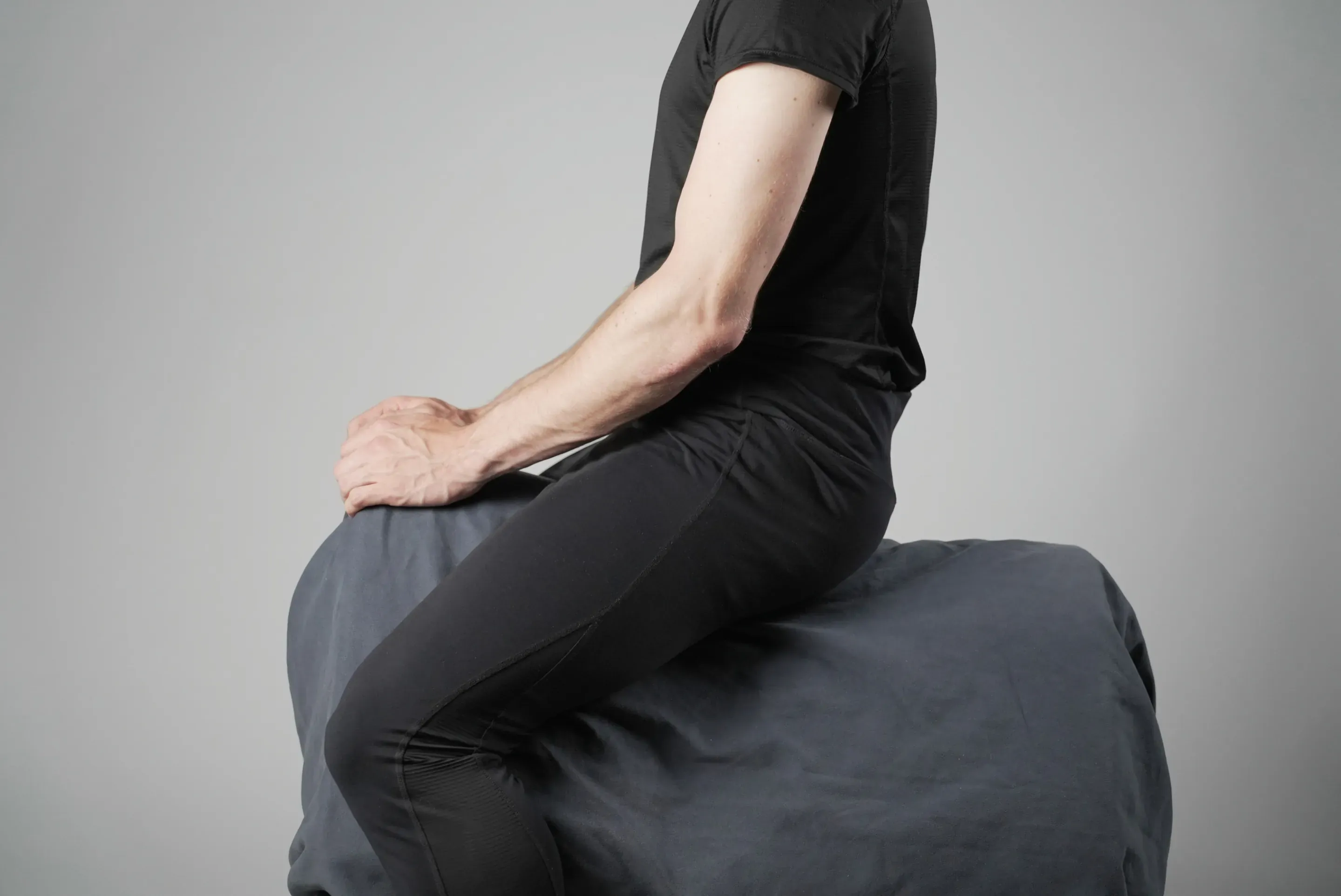 Seat study: the same setup, the person sits upright with a hand resting on the front of the block.