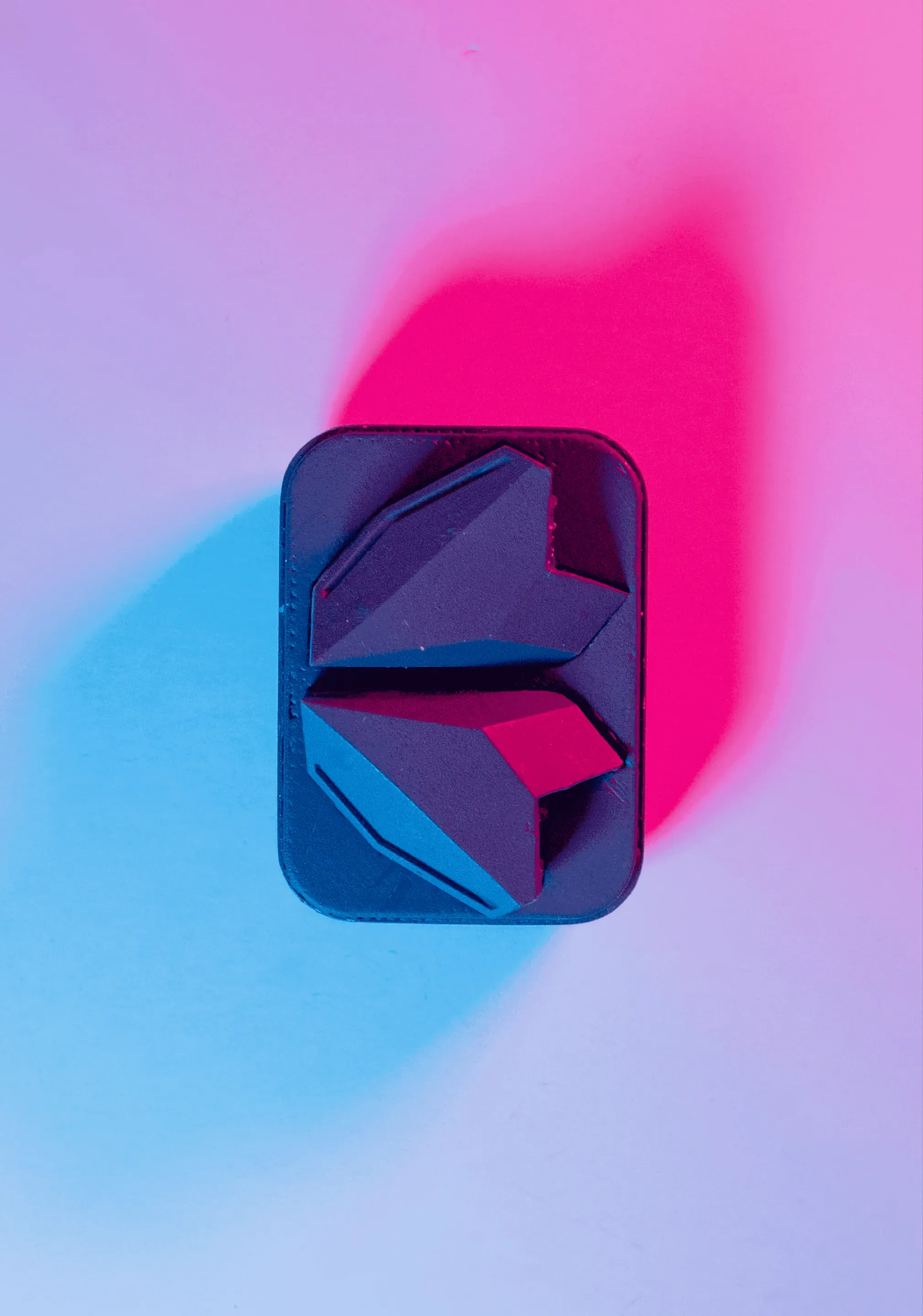 Two earbud prototypes lying in a dark case with rounded corners, seen from above on a white ground lit pink and light blue.