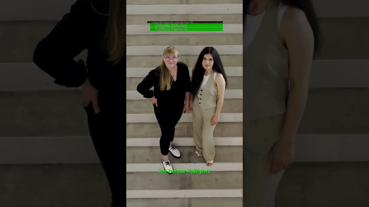 Film still: two women stand side by side on outdoor steps, with green lines of text over the picture.
